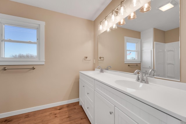 full bathroom featuring double vanity, baseboards, a sink, and wood finished floors