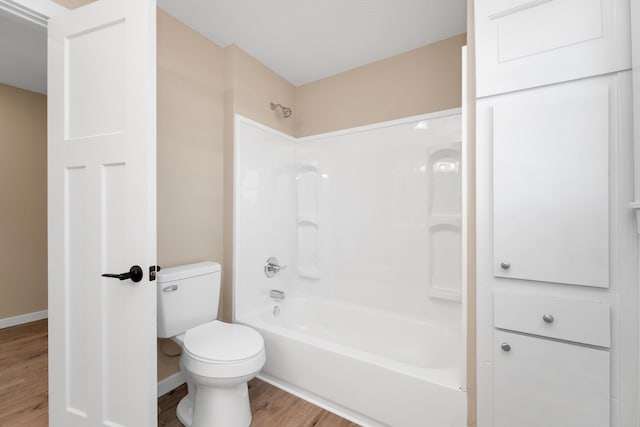 bathroom with shower / bathtub combination, baseboards, toilet, and wood finished floors