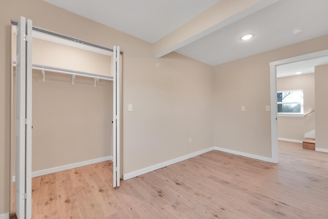 unfurnished bedroom with a closet, beam ceiling, baseboards, light wood-type flooring, and recessed lighting