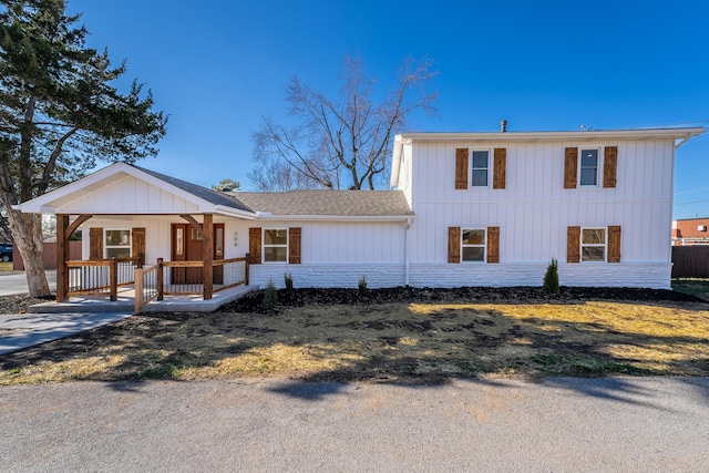 view of front facade with a shingled roof, board and batten siding, and covered porch