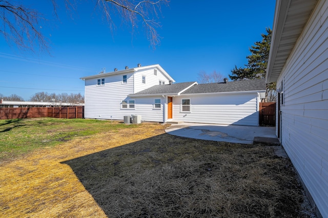 back of property with a patio, a fenced backyard, a lawn, and central AC