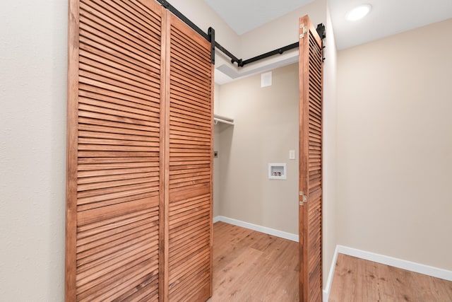 hall with baseboards, light wood-style flooring, and a barn door