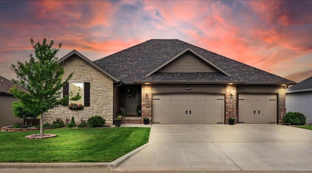 view of front of home with stone siding, an attached garage, driveway, and a front yard