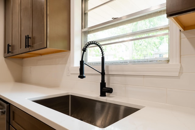 interior details with a sink, light countertops, tasteful backsplash, and dark brown cabinetry
