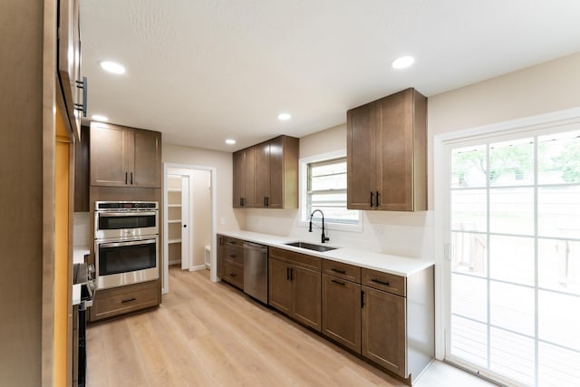kitchen featuring a sink, light countertops, light wood-style flooring, stainless steel appliances, and recessed lighting