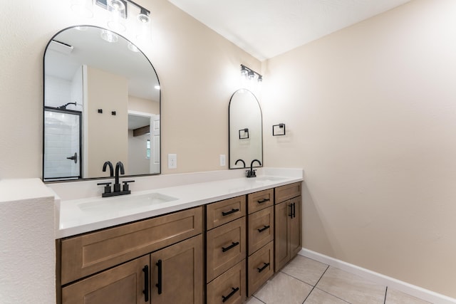 bathroom with double vanity, a sink, tile patterned floors, and tiled shower