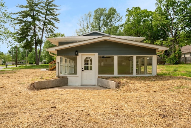 view of outdoor structure with fence and a sunroom