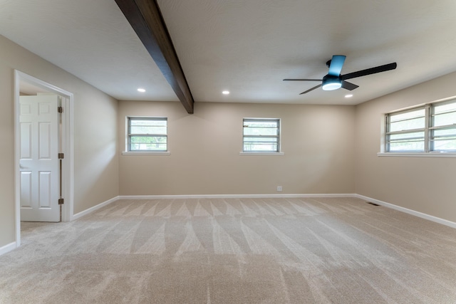 unfurnished room featuring baseboards, beam ceiling, a wealth of natural light, and light carpet