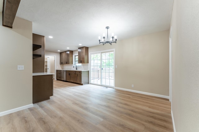 kitchen featuring an inviting chandelier, light countertops, light wood-style floors, and dishwasher