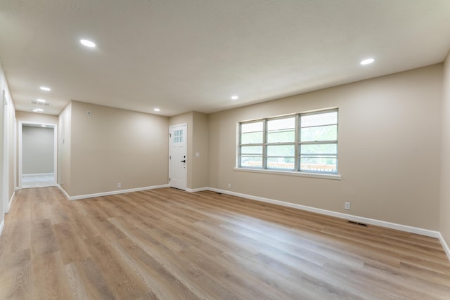 empty room with baseboards, light wood-type flooring, recessed lighting, and visible vents