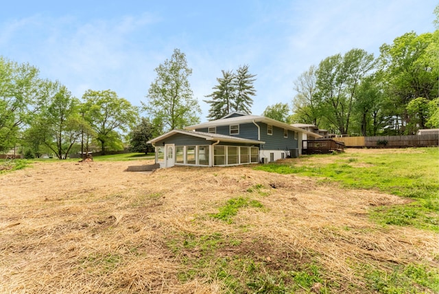 back of property with fence and a sunroom