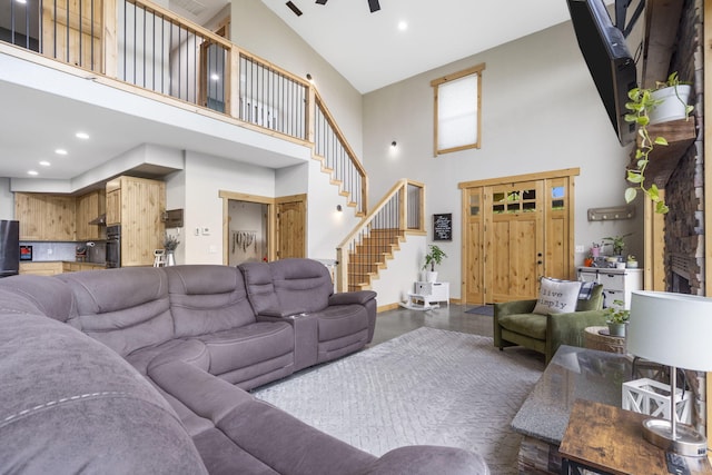 living area with stairway, ceiling fan, recessed lighting, and a towering ceiling