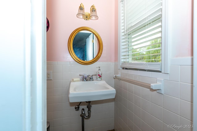 bathroom with tile walls, a wainscoted wall, and a sink