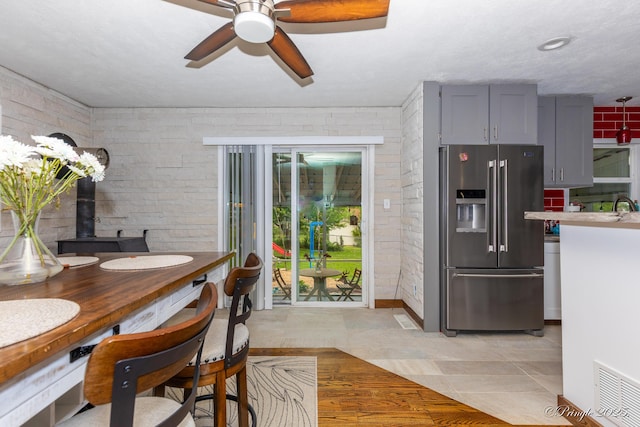 dining area featuring ceiling fan, brick wall, and visible vents