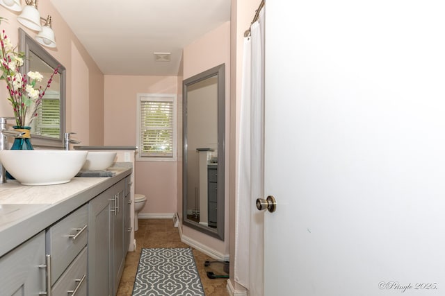bathroom featuring toilet, a shower, vanity, tile patterned floors, and baseboards