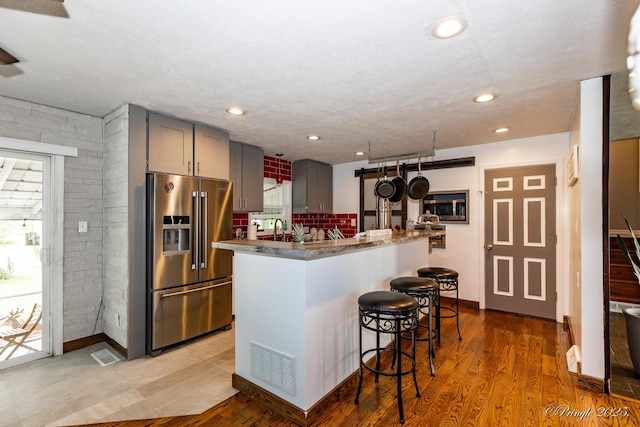 kitchen featuring visible vents, a sink, a kitchen breakfast bar, appliances with stainless steel finishes, and gray cabinets