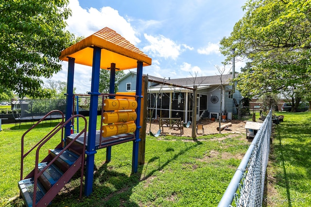 view of play area featuring a lawn, a trampoline, and fence