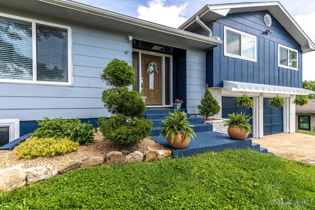 entrance to property with an attached garage, concrete driveway, and board and batten siding