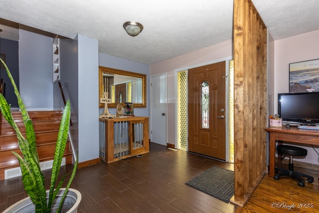 foyer entrance featuring visible vents, wood finished floors, and baseboards