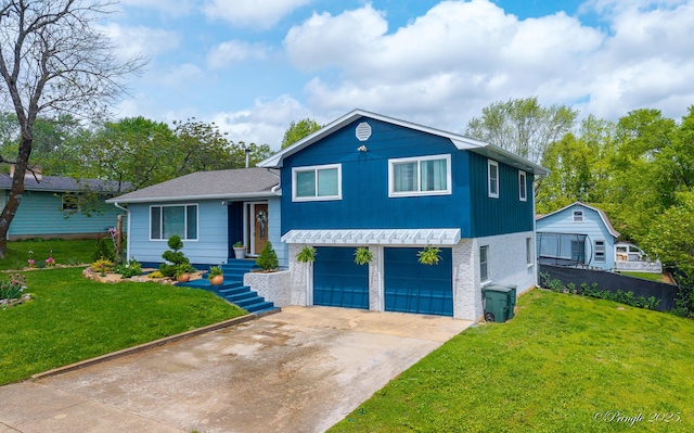 split level home featuring concrete driveway, a front lawn, an attached garage, and fence