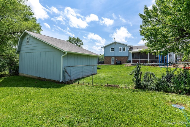 view of yard featuring fence, a sunroom, and an outbuilding
