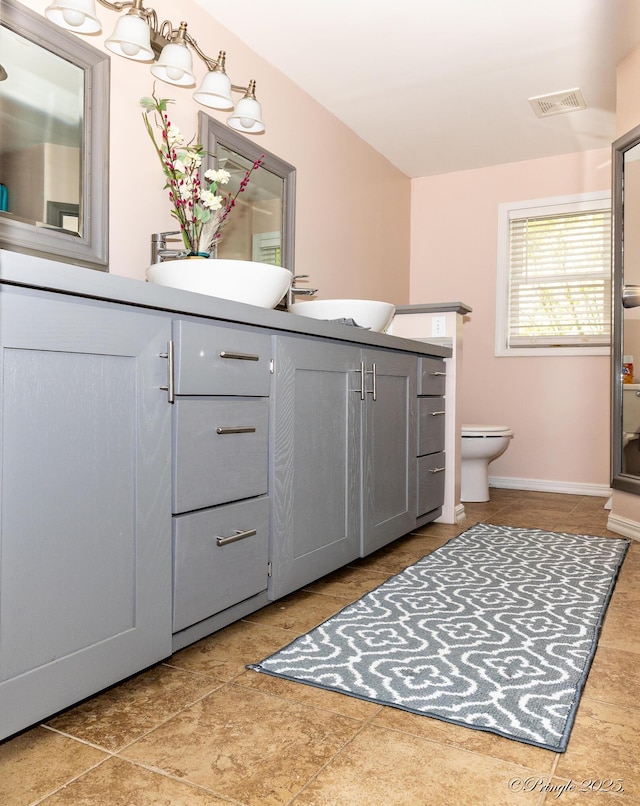 full bathroom with a sink, toilet, visible vents, tile patterned floors, and double vanity