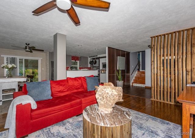 living area featuring stairs, a ceiling fan, visible vents, and wood finished floors