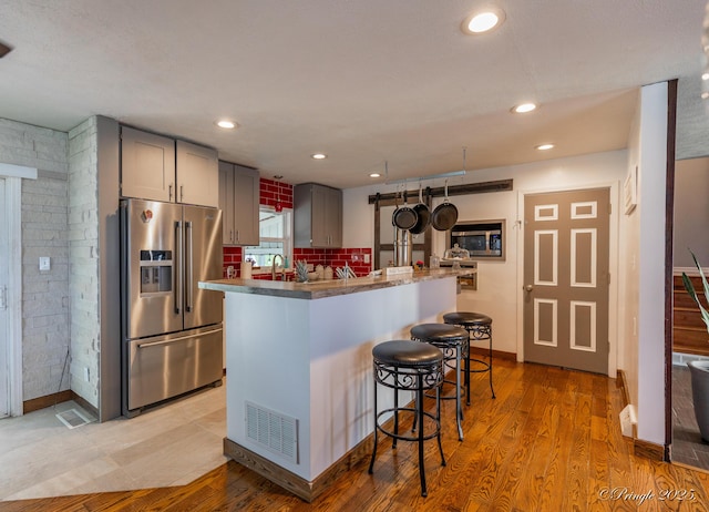 kitchen featuring light wood-type flooring, visible vents, a kitchen bar, gray cabinetry, and appliances with stainless steel finishes