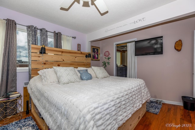 bedroom featuring ceiling fan, a textured ceiling, baseboards, and wood finished floors