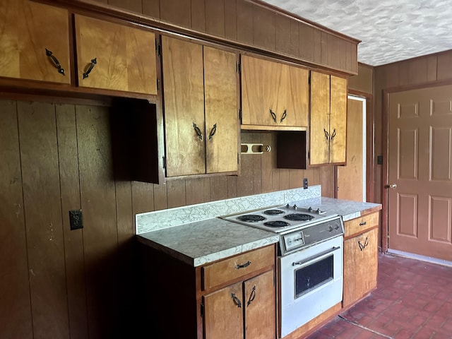 kitchen with brown cabinets, white electric range oven, wood walls, and brick floor