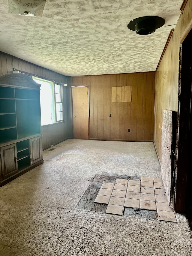 spare room featuring wooden walls, a textured ceiling, and carpet