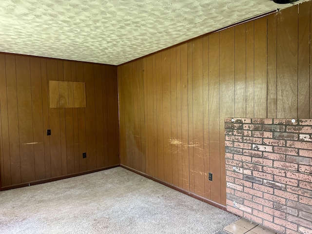 carpeted empty room with wood walls and a textured ceiling