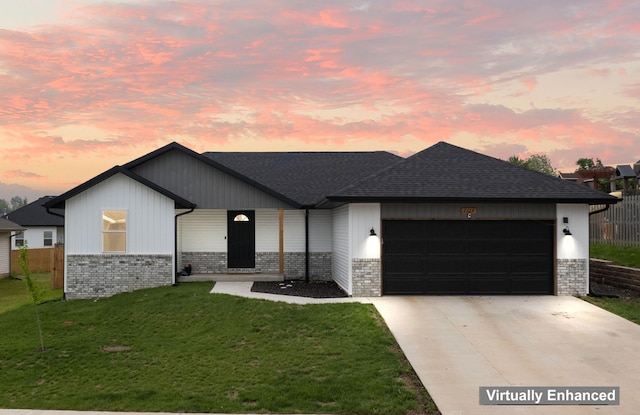 view of front facade with an attached garage, driveway, a yard, and brick siding