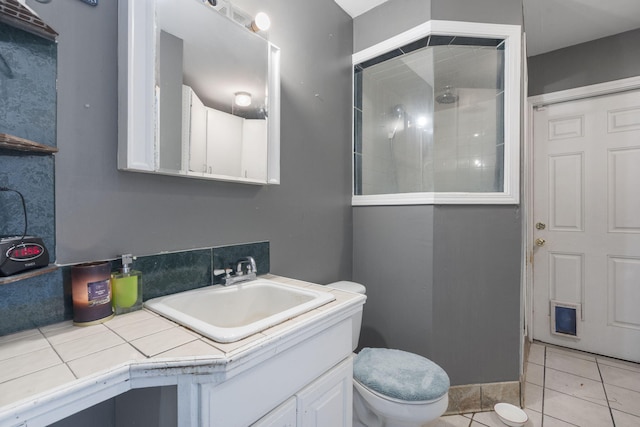 bathroom with toilet, a tile shower, tile patterned flooring, and vanity