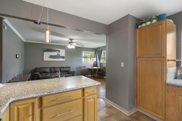 kitchen featuring a ceiling fan, decorative light fixtures, light stone countertops, baseboards, and open floor plan