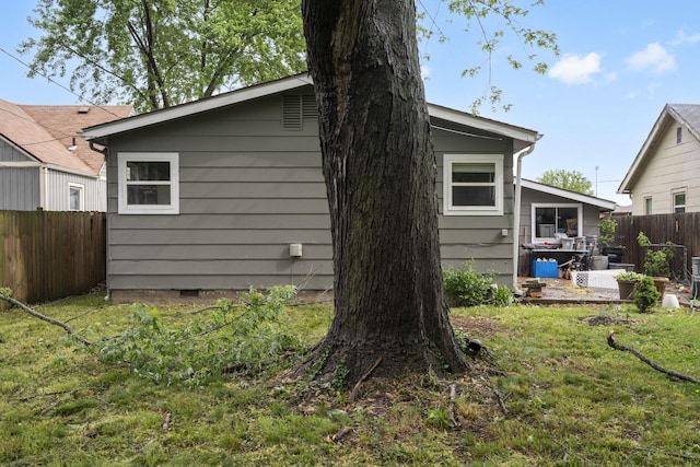 back of property featuring fence, a lawn, and crawl space