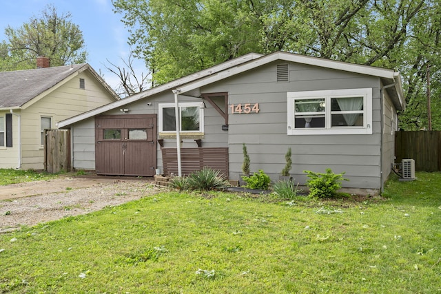 view of front of home with fence, central AC, and a front lawn