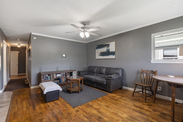 living area with baseboards, ceiling fan, ornamental molding, and wood finished floors