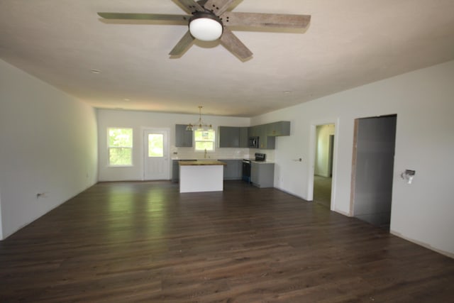 unfurnished living room with dark wood-style floors and ceiling fan with notable chandelier