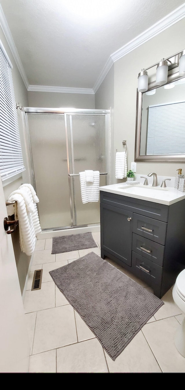 bathroom featuring visible vents, crown molding, tile patterned flooring, a stall shower, and vanity