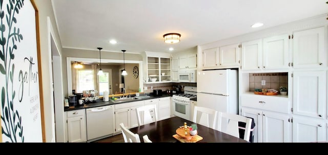 kitchen featuring white cabinets, dark countertops, a sink, white appliances, and backsplash