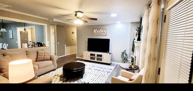 living room with crown molding, a ceiling fan, baseboards, and wood finished floors
