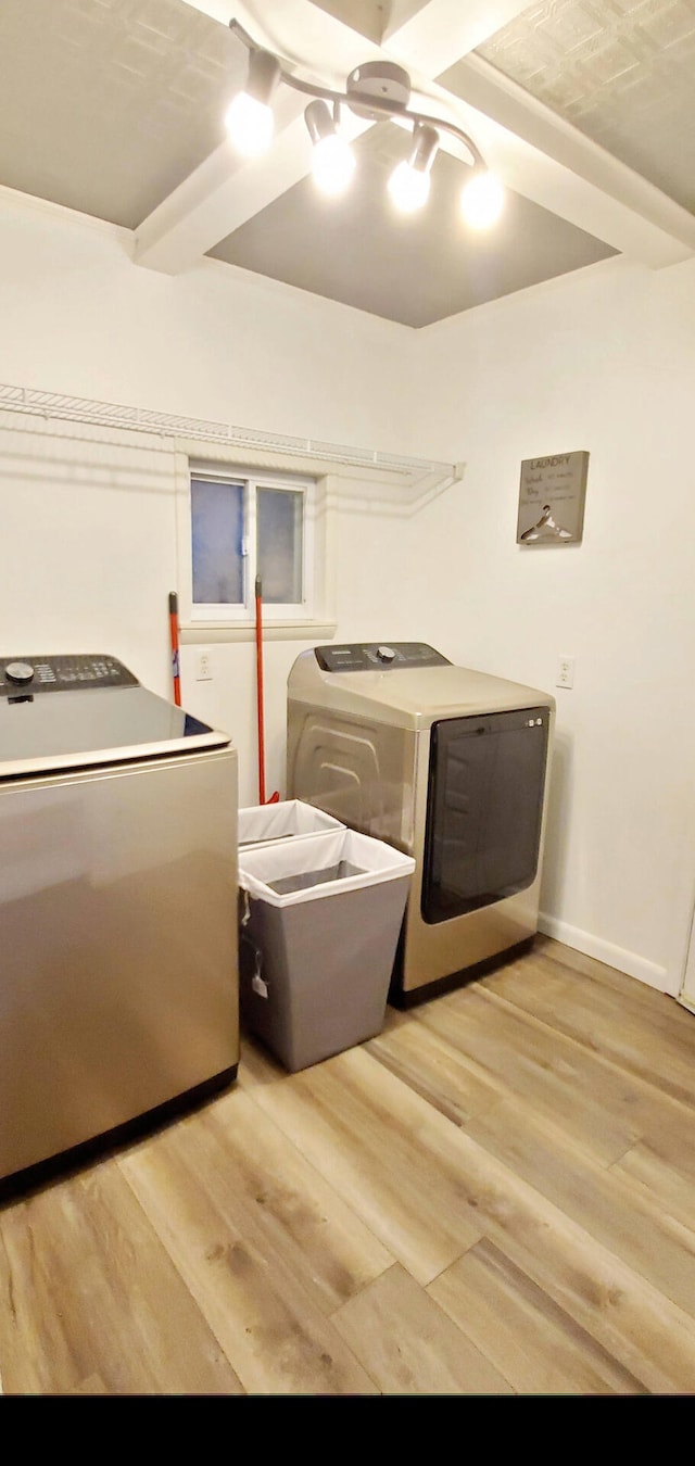 laundry room featuring separate washer and dryer, laundry area, light wood-style flooring, and baseboards