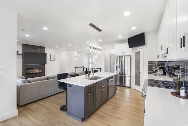 635 W Bridgewood Ct, Springfield, MO 65803 - kitchen with stainless steel appliances, a sink, a fireplace, white cabinets, and light wood-style floors