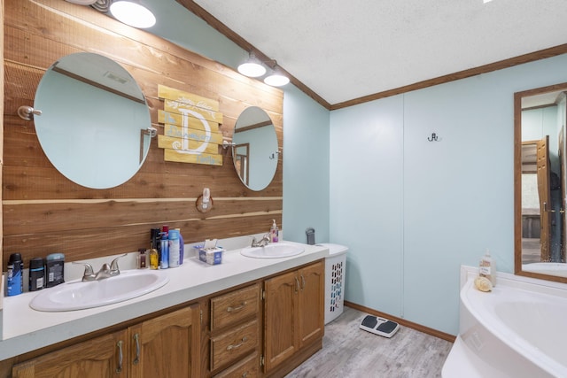 full bath featuring crown molding, wooden walls, and a sink