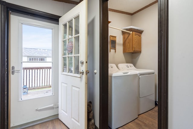 washroom with cabinet space, crown molding, washing machine and dryer, and wood finished floors