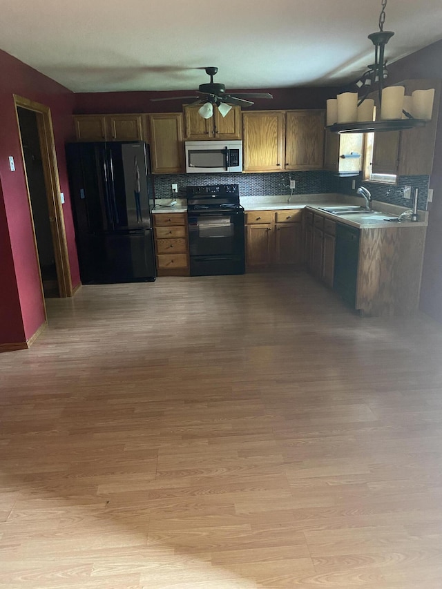 kitchen featuring a ceiling fan, backsplash, black appliances, and light wood finished floors