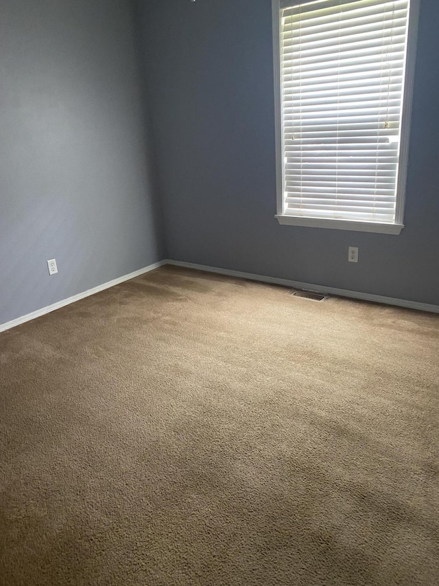 carpeted empty room featuring baseboards and visible vents