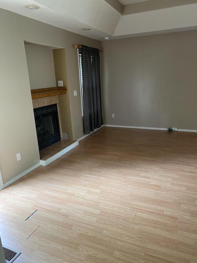 unfurnished living room featuring light wood-style floors, baseboards, and a tile fireplace