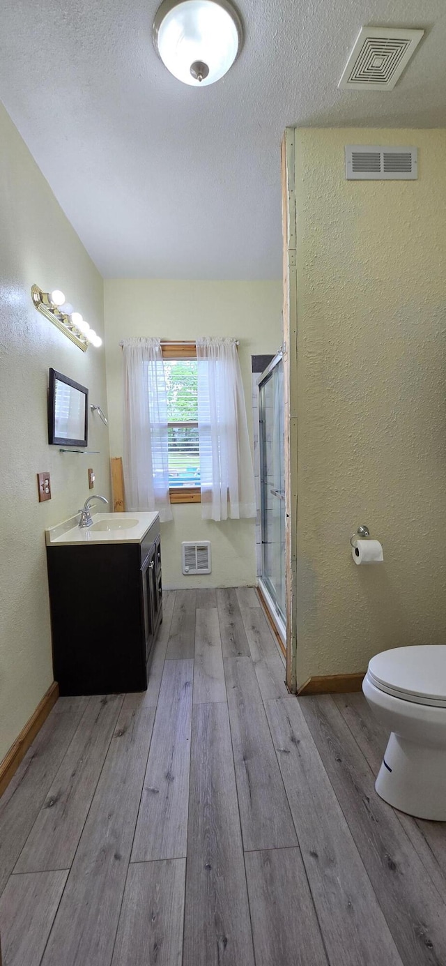 full bath featuring wood-type flooring, a shower stall, and visible vents